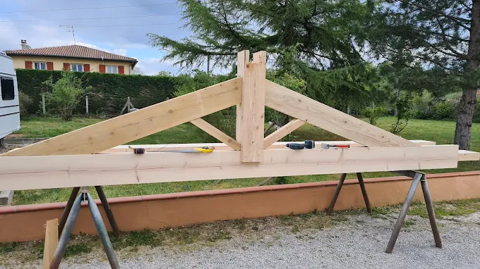 Fabrication d'une ferme de charpente bois sur-mesure par SCM82 — atelier extérieur